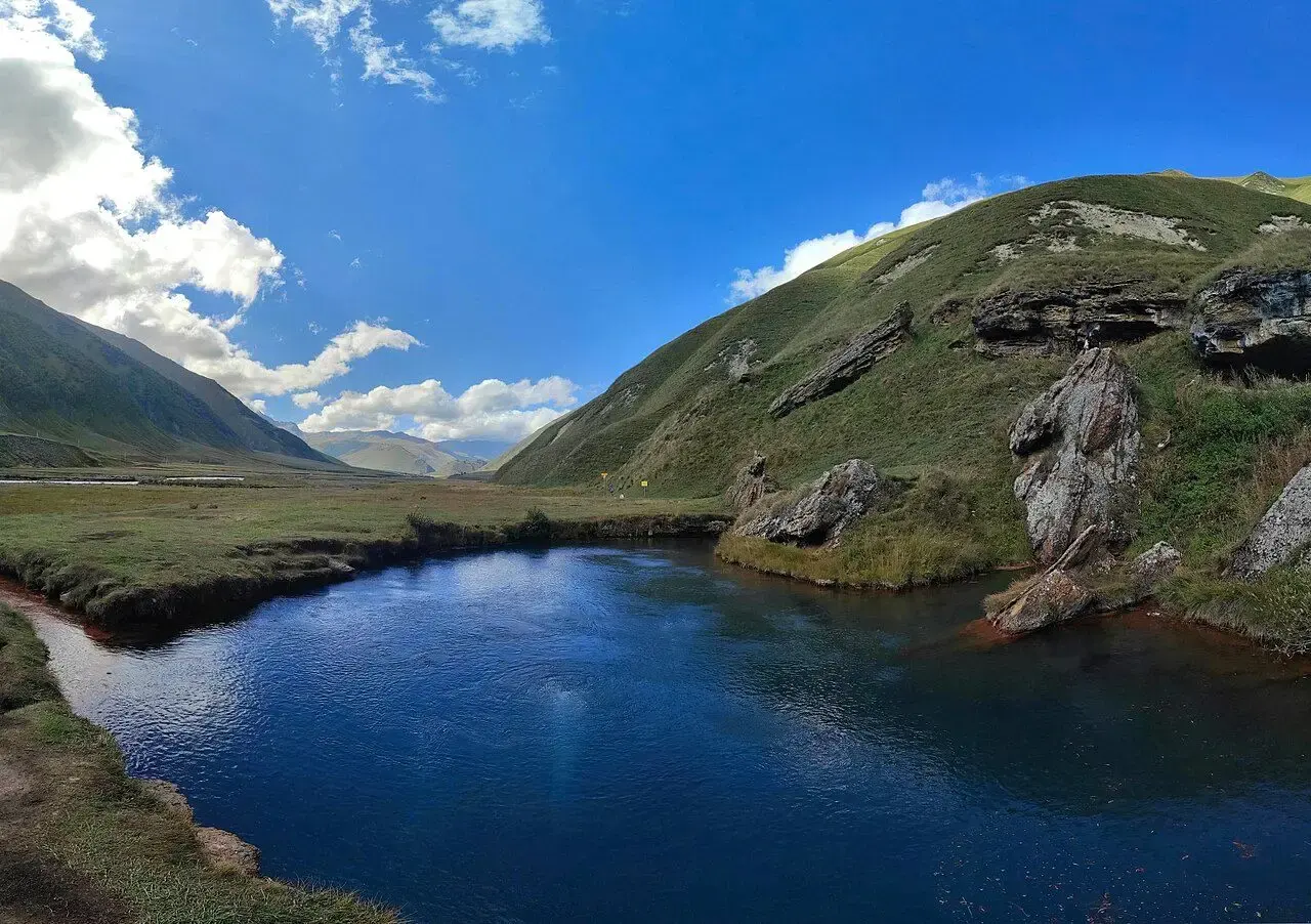 Dark blue Abano mineral lake below grassy slopes