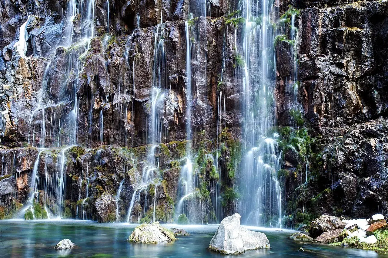 Many thin waterfalls pouring over dark basalt in Dashbashi Canyon
