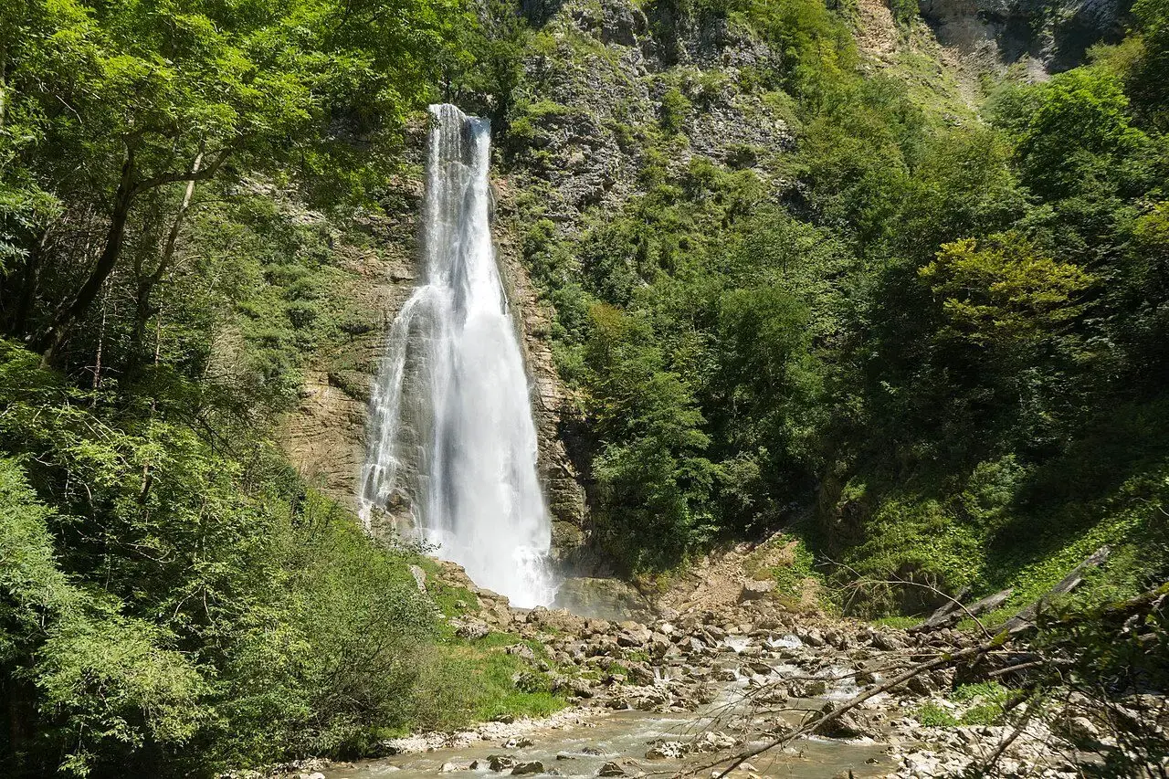 Oniore waterfall falling into a green gorge
